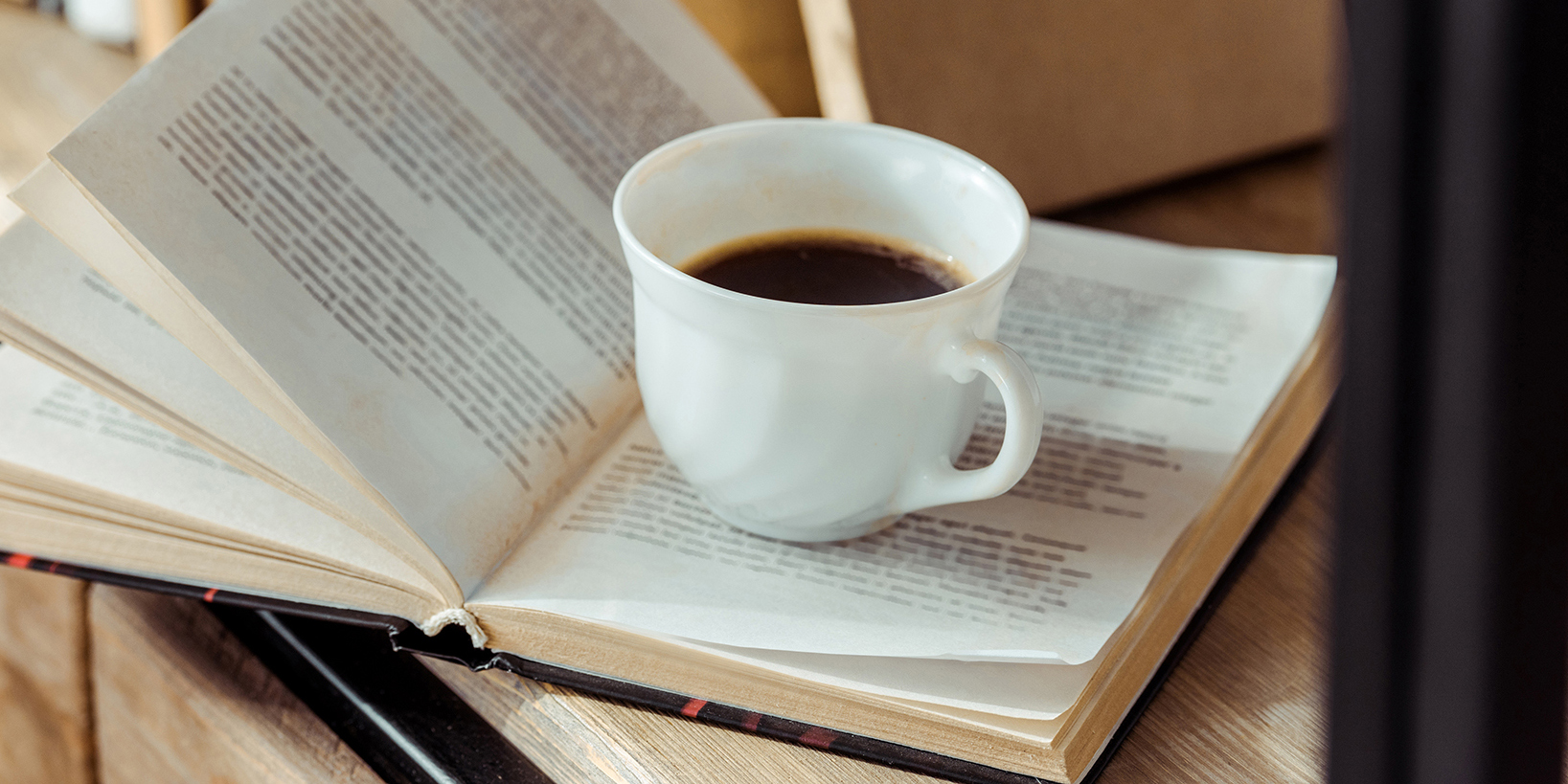 Buch mit Tasse Kaffee auf Schreibtisch